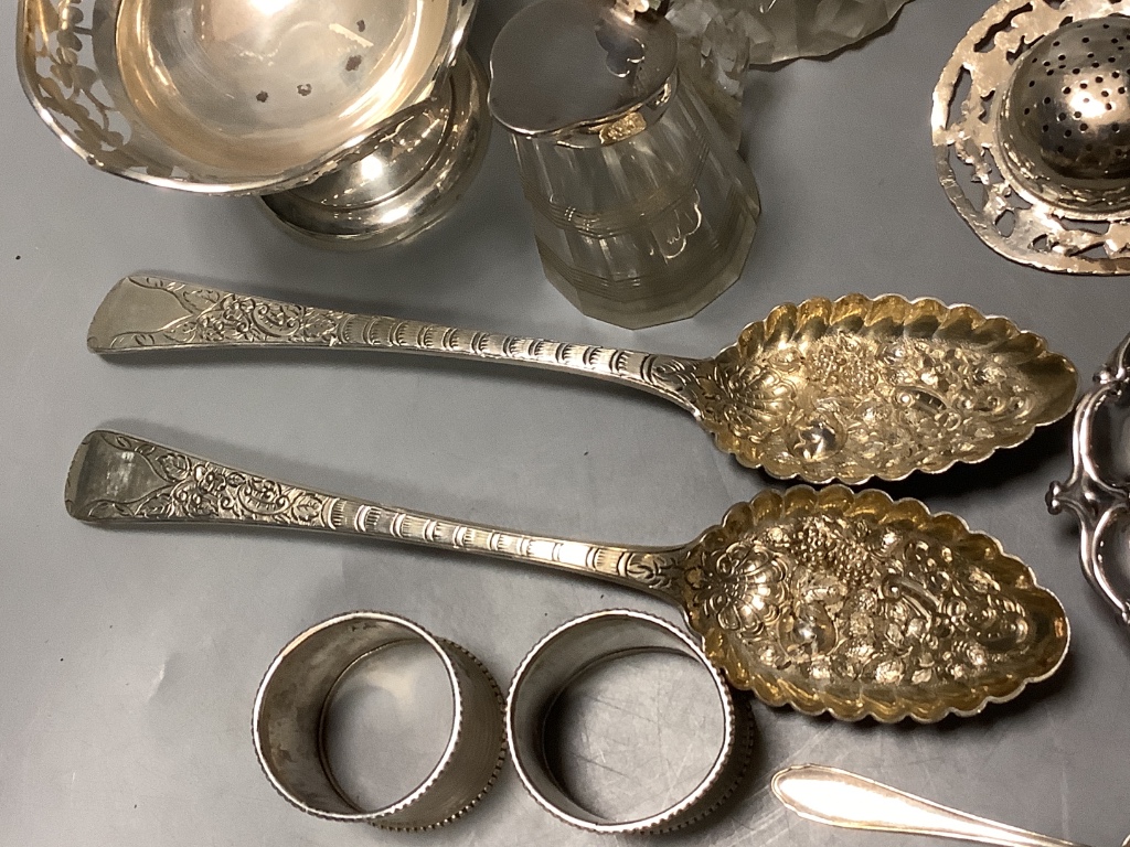 A mixed group of silver including a pair of George III silver Berry spoons, a pair of silver napkin rings, silver nut dish, white metal tea strainer a silver mounted whisky tot jug, 800 spoon, small silver pedestal bowl